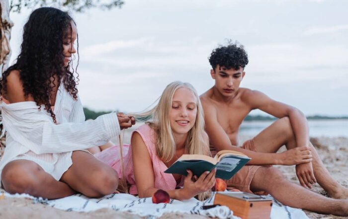 high school students reading a book at the beach
