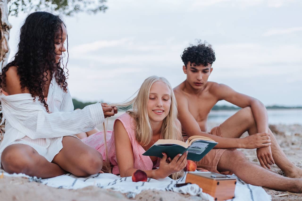 high school students reading a book at the beach