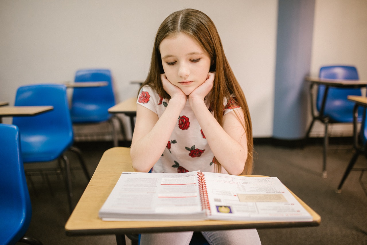 young girl sitting in class reading