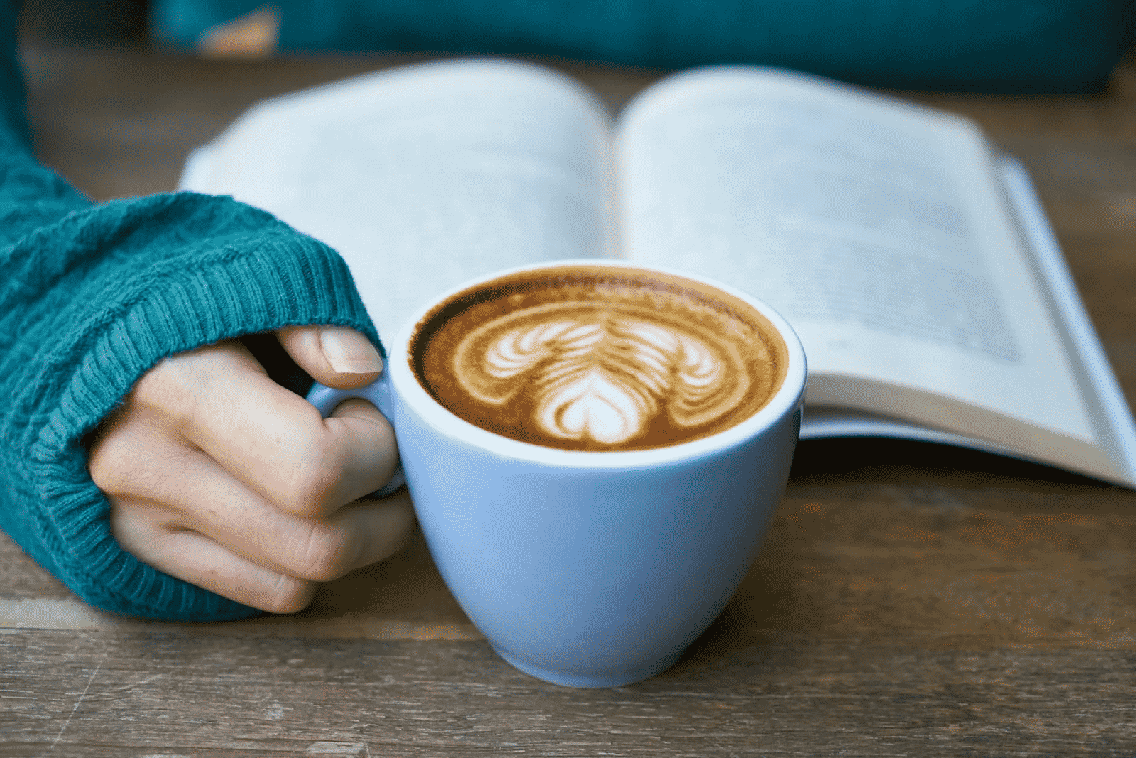 Person reading a book with a coffee in front of them