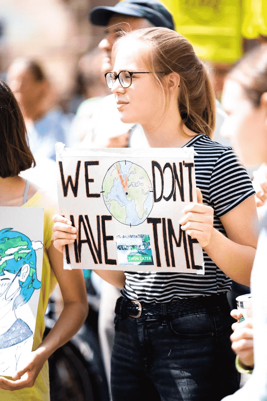 student holding a sign "we don't have time"
