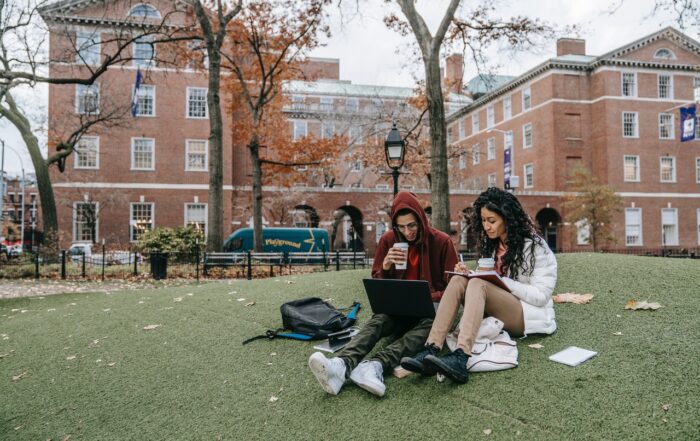 two students sitting down and reading on a college campus