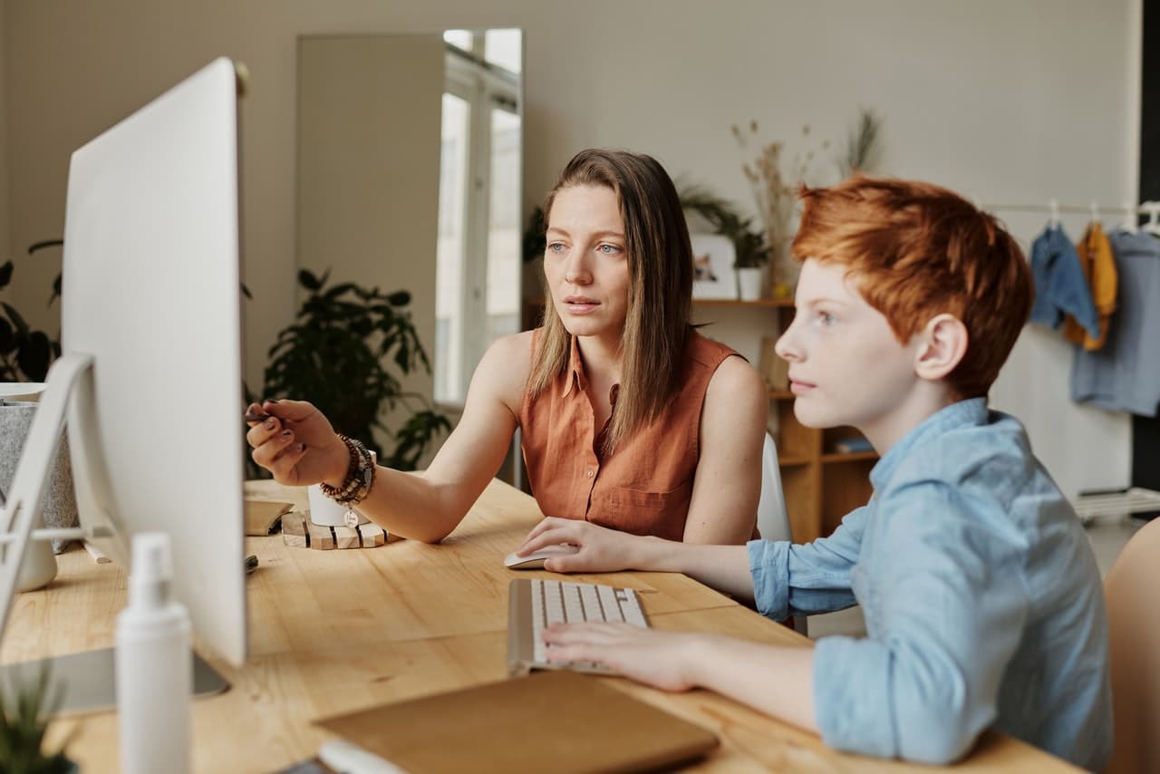 Photo of teacher and a student working on a computer