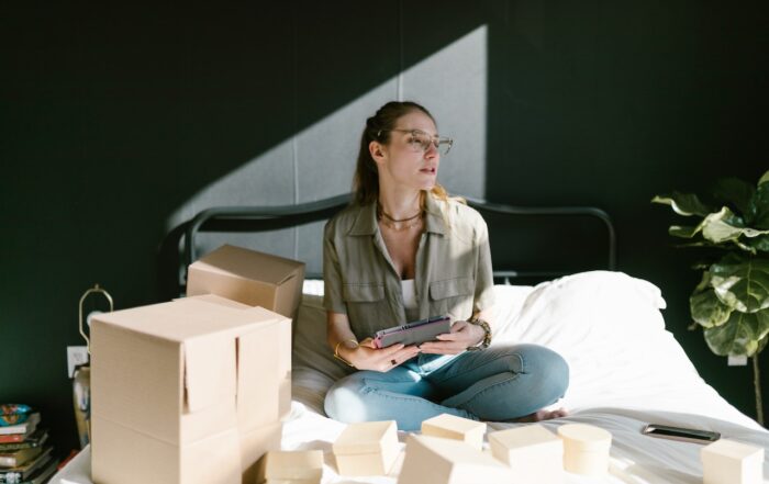 A Woman in Bed with Brown Boxes while Holding a Tablet